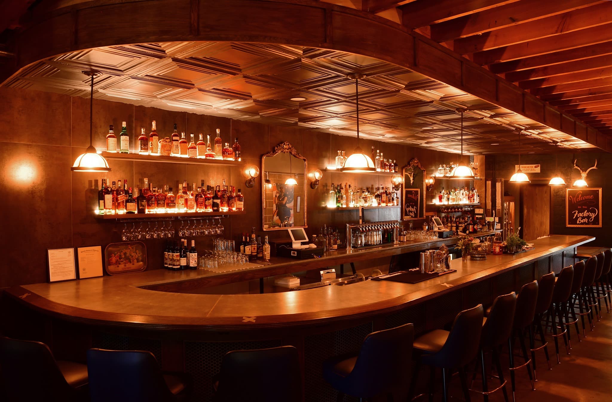 Cozy bar interior with warm lighting and bottles.