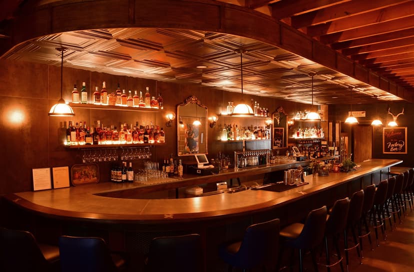 Cozy bar interior with warm lighting and bottles.