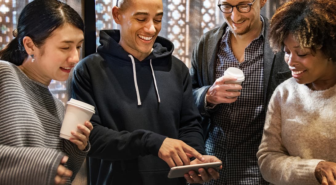 Group enjoying coffee and smartphone together indoors.