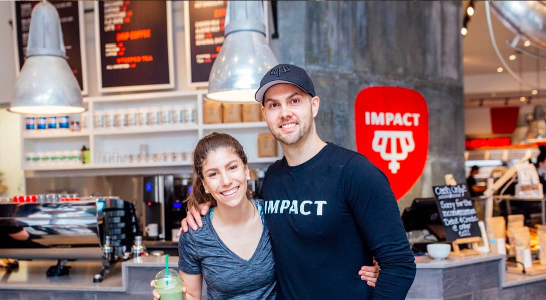 Smiling cafe staff wearing Impact shirts.