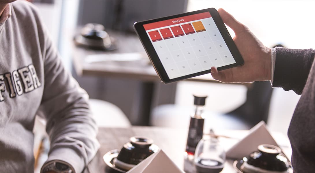 Person showing calendar app on tablet in restaurant.