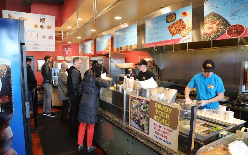 Customers ordering at a fast-casual restaurant counter.