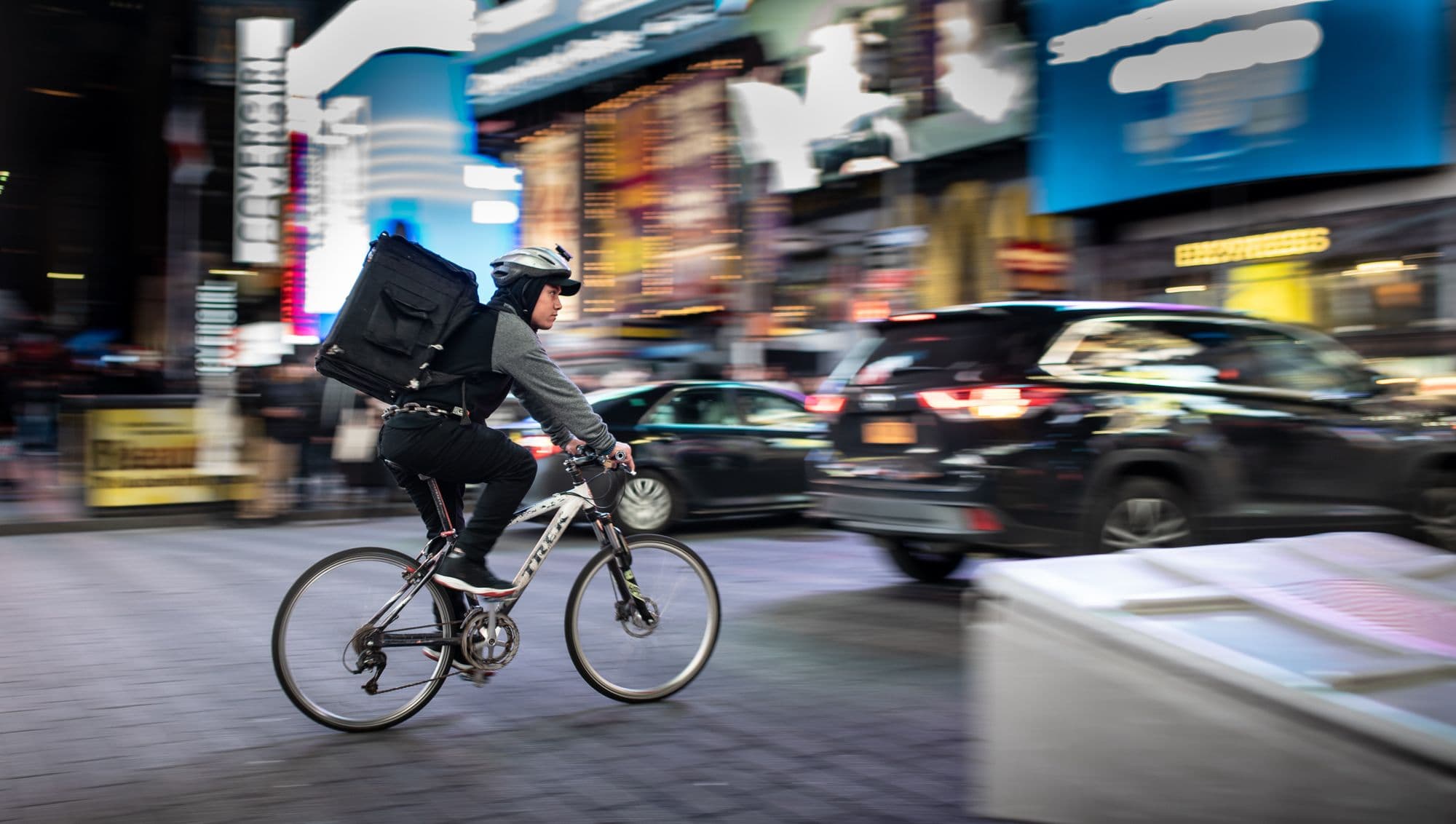 Cyclist delivering food in busy city street.