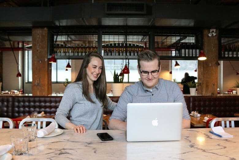 Two people working on a laptop in a cafe.