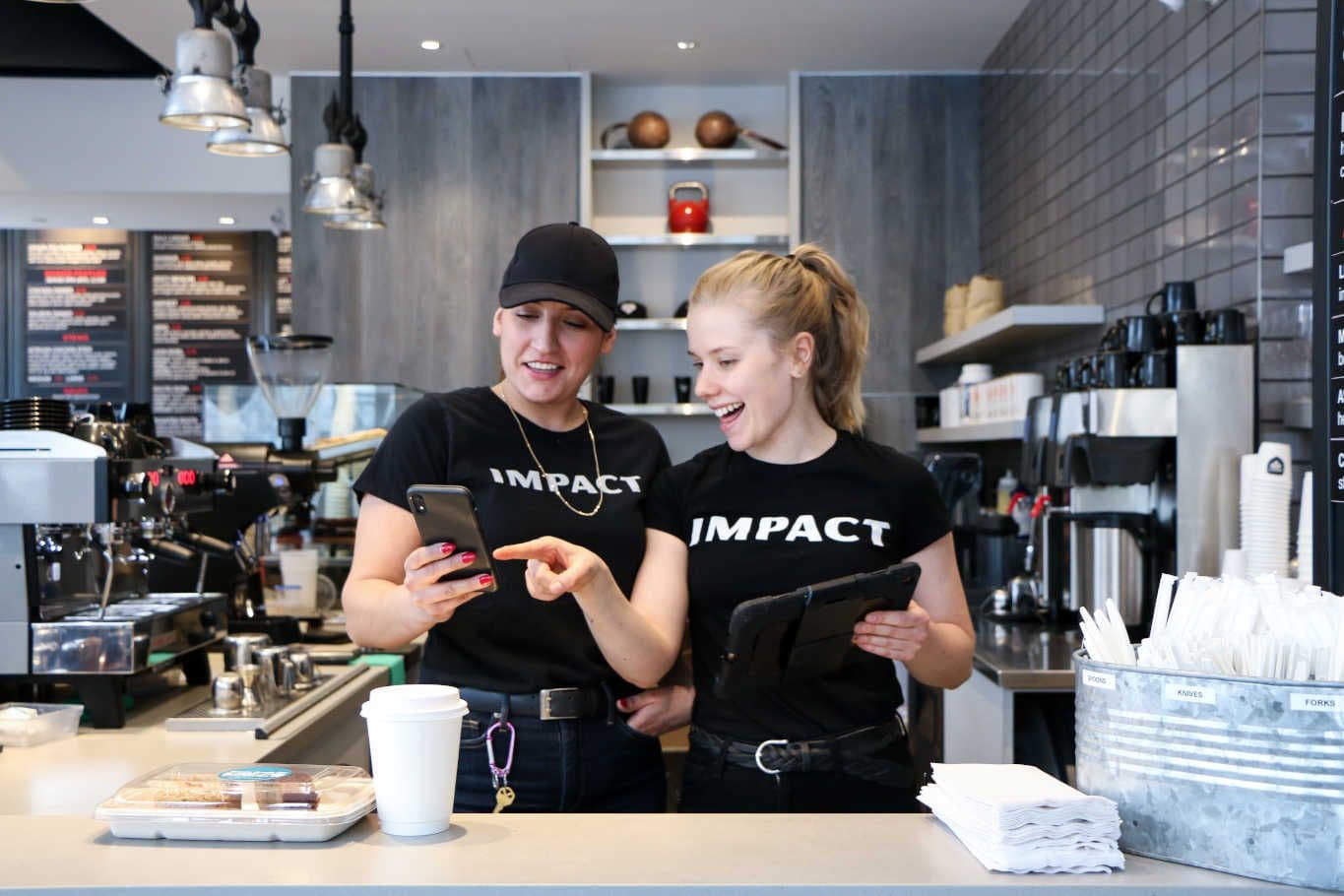 Baristas smiling and checking phone in cafe