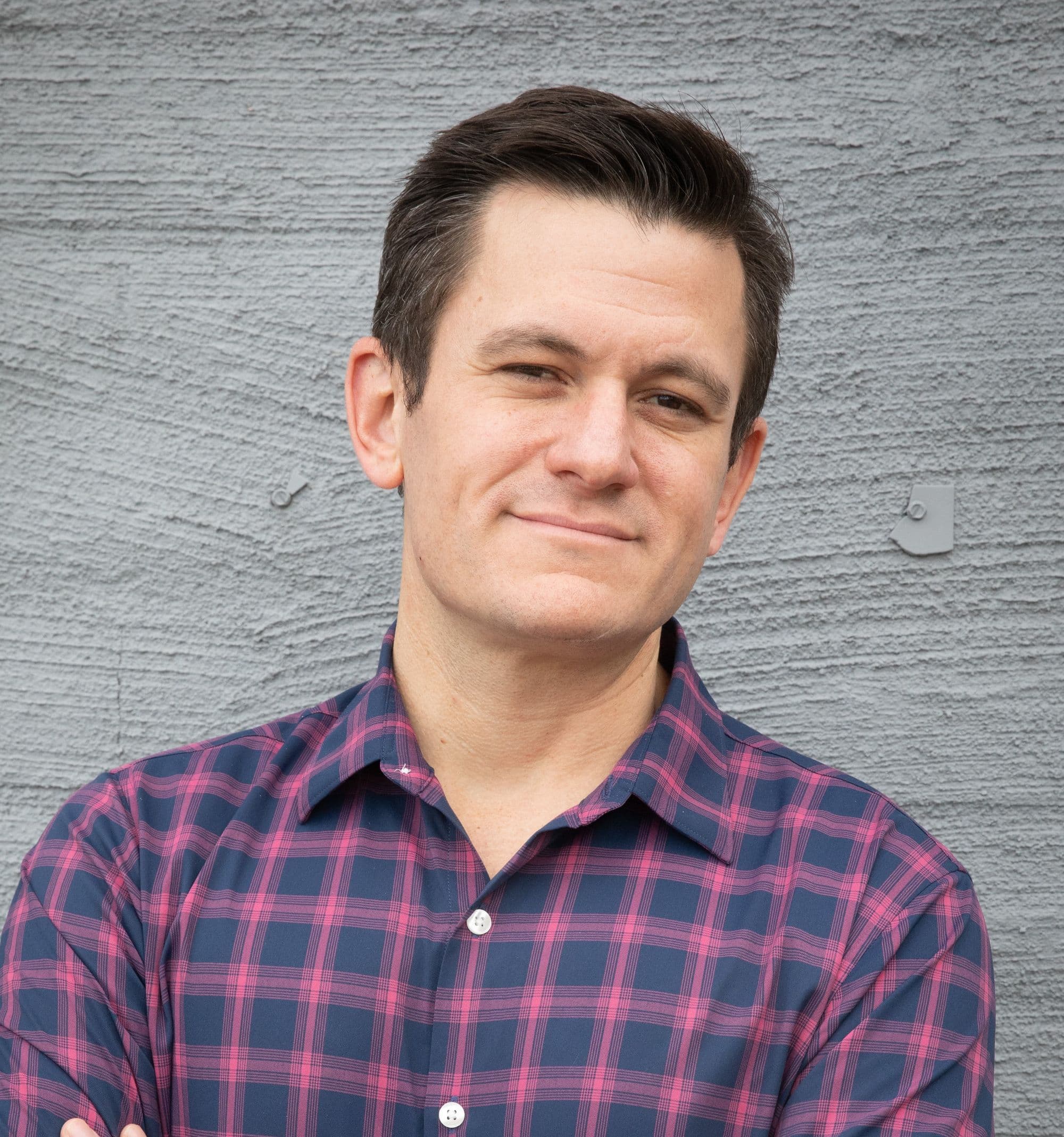 Person in checkered shirt against gray textured wall.