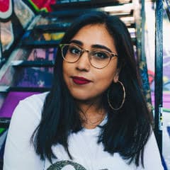 Woman sitting on graffiti-covered urban stairs, smiling.